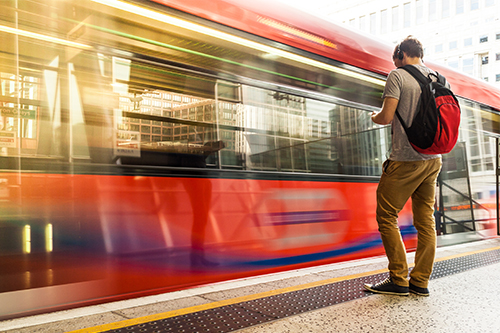 Young man with backpack and headphones waiting for train